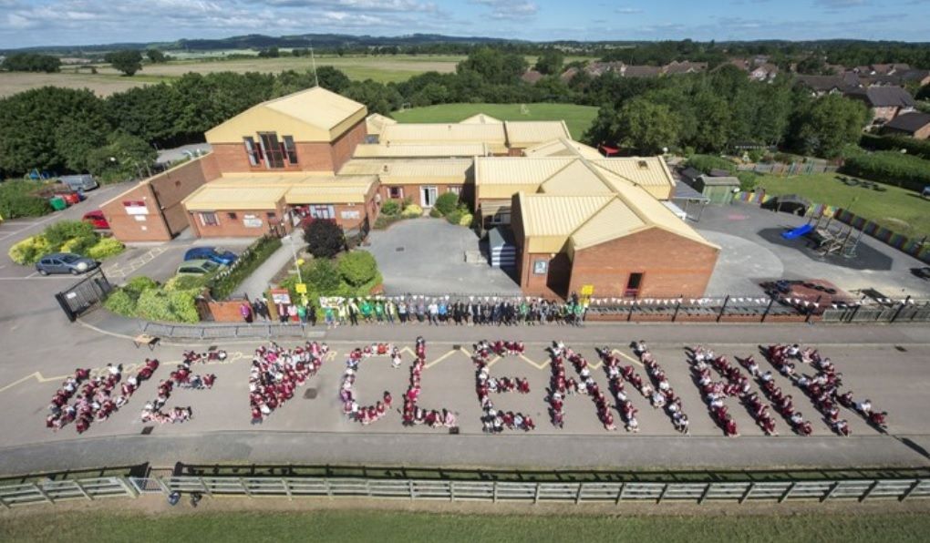 Aerial view of children spelling out “We (heart) clean air” in front of school buildings